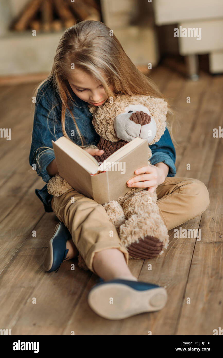 kleines Mädchen mit Teddybär Buch zu lesen, konzentriert Bildungskonzept für Kinder Stockfoto