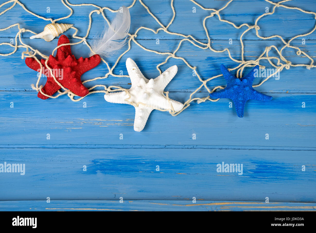 rot weiß und blau Seestern in nautischen Saldierung mit Muschel und Feder auf rustikalen blau Holz Stockfoto