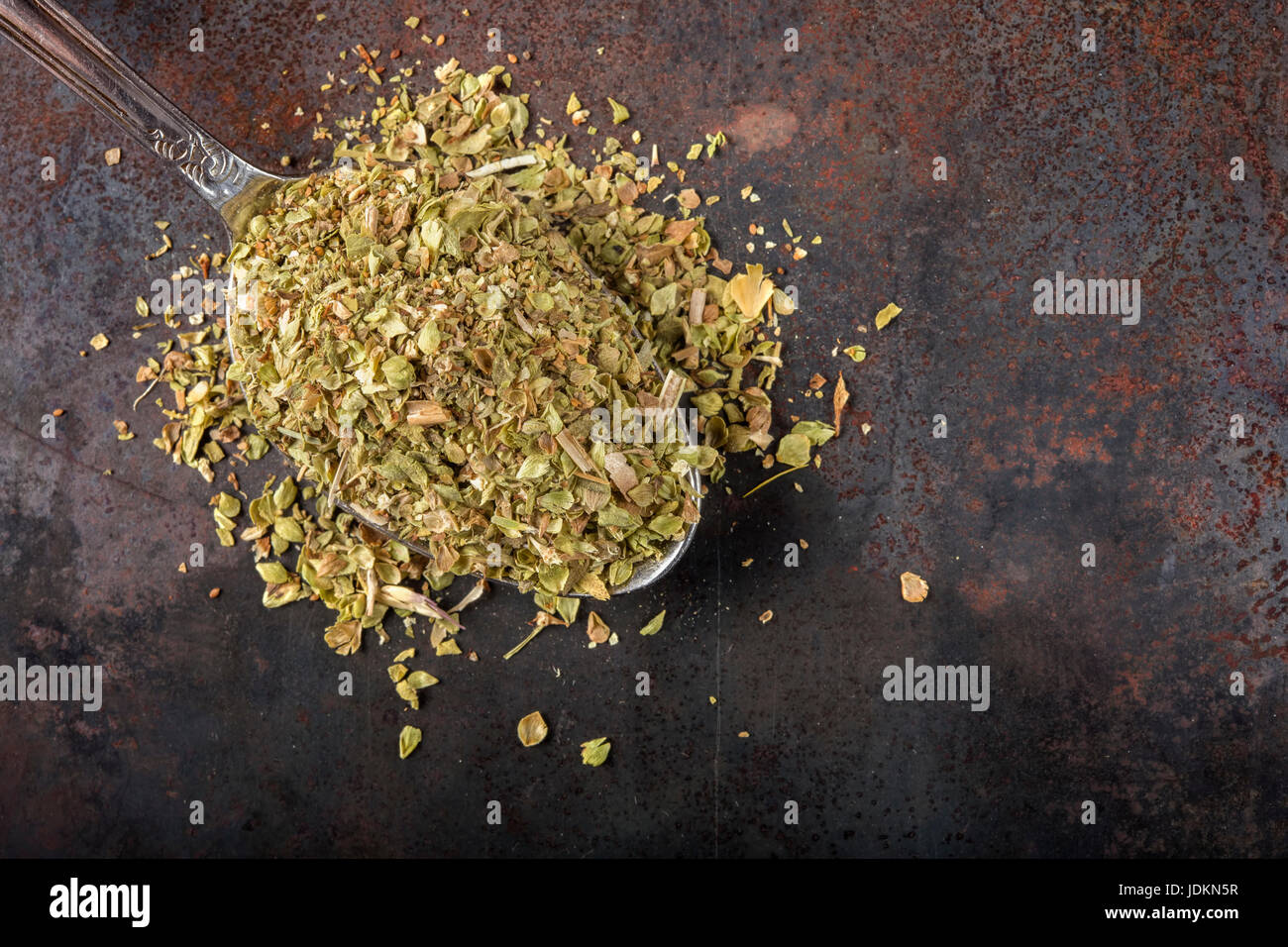 Löffel gefüllt mit getrockneten Oregano auf rostigen Hintergrund mit Textfreiraum Stockfoto
