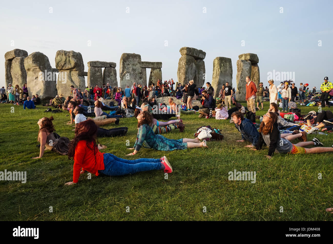 Sommersonnenwende feiern in Stonehenge. Menschen üben Yoga bei Sonnenaufgang, Stonehenge, Wiltshire, England, Vereinigtes Königreich, Großbritannien Stockfoto