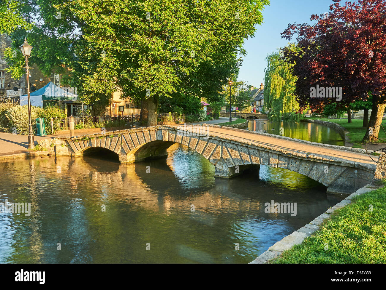 Ein Sommermorgen und kleinen steinernen Stege über den Fluss Windrush im malerischen Cotswolds Dorf von Bourton auf dem Wasser, Gloucestershire Stockfoto