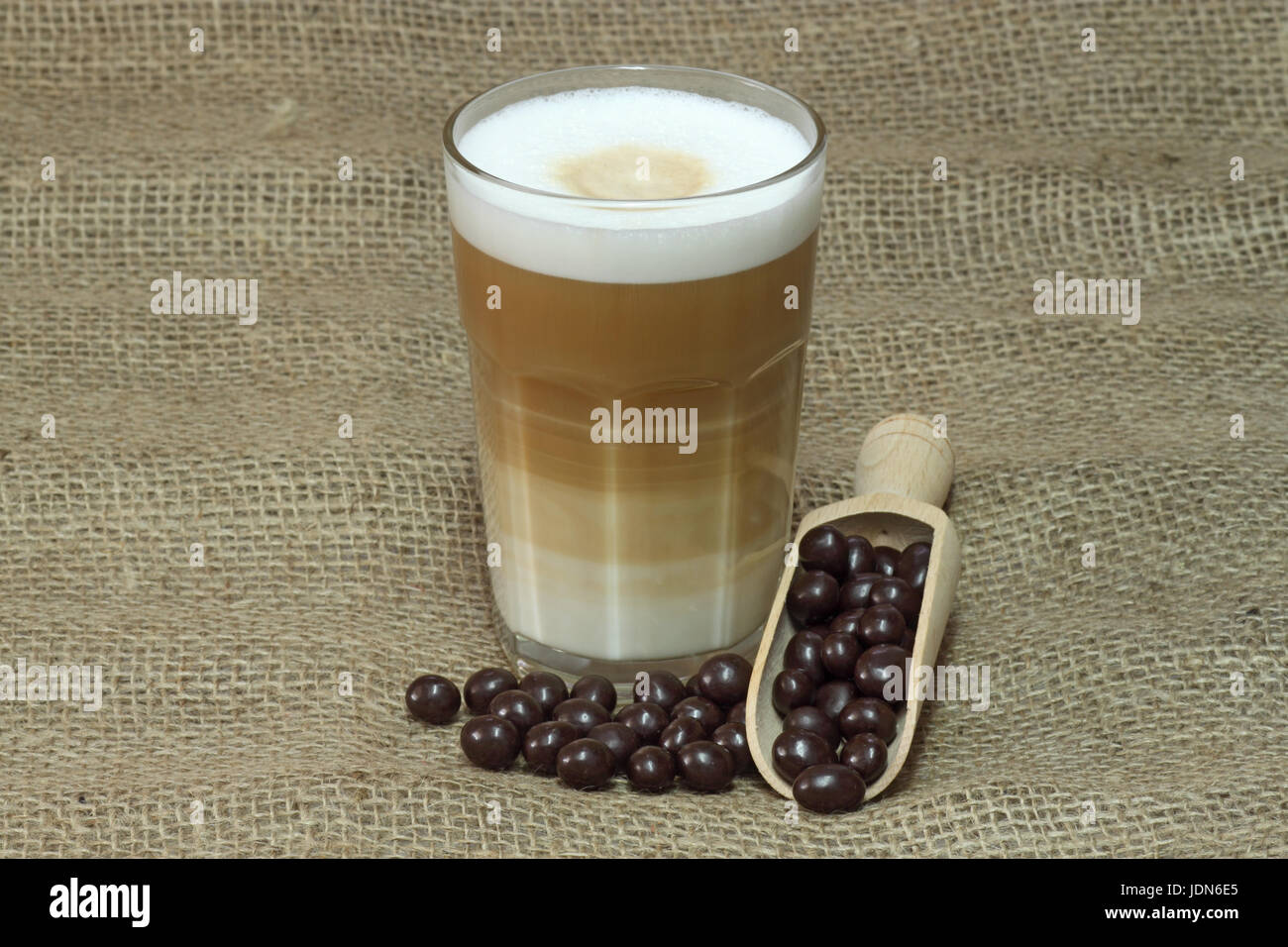 Latte Macchiato im Glas mit Kaffee Korn auf braunem Hintergrund Stockfoto