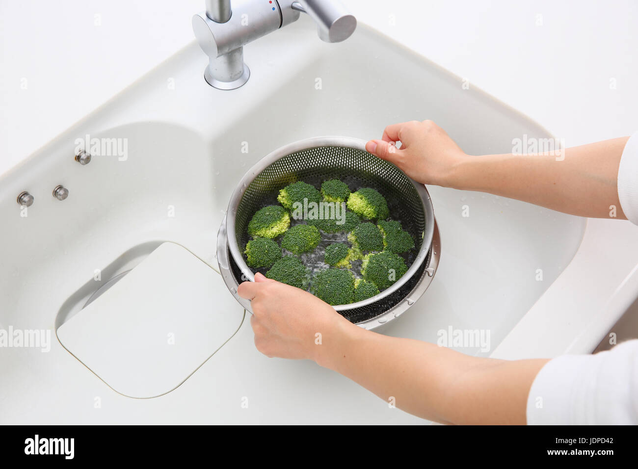 Japanische Frau waschen Brokkoli in der Küche Stockfoto