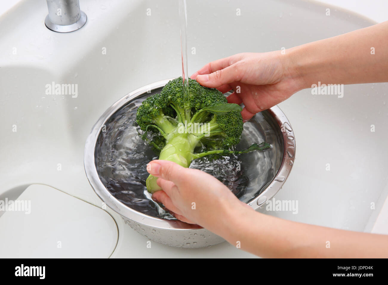 Japanische Frau waschen Brokkoli in der Küche Stockfoto