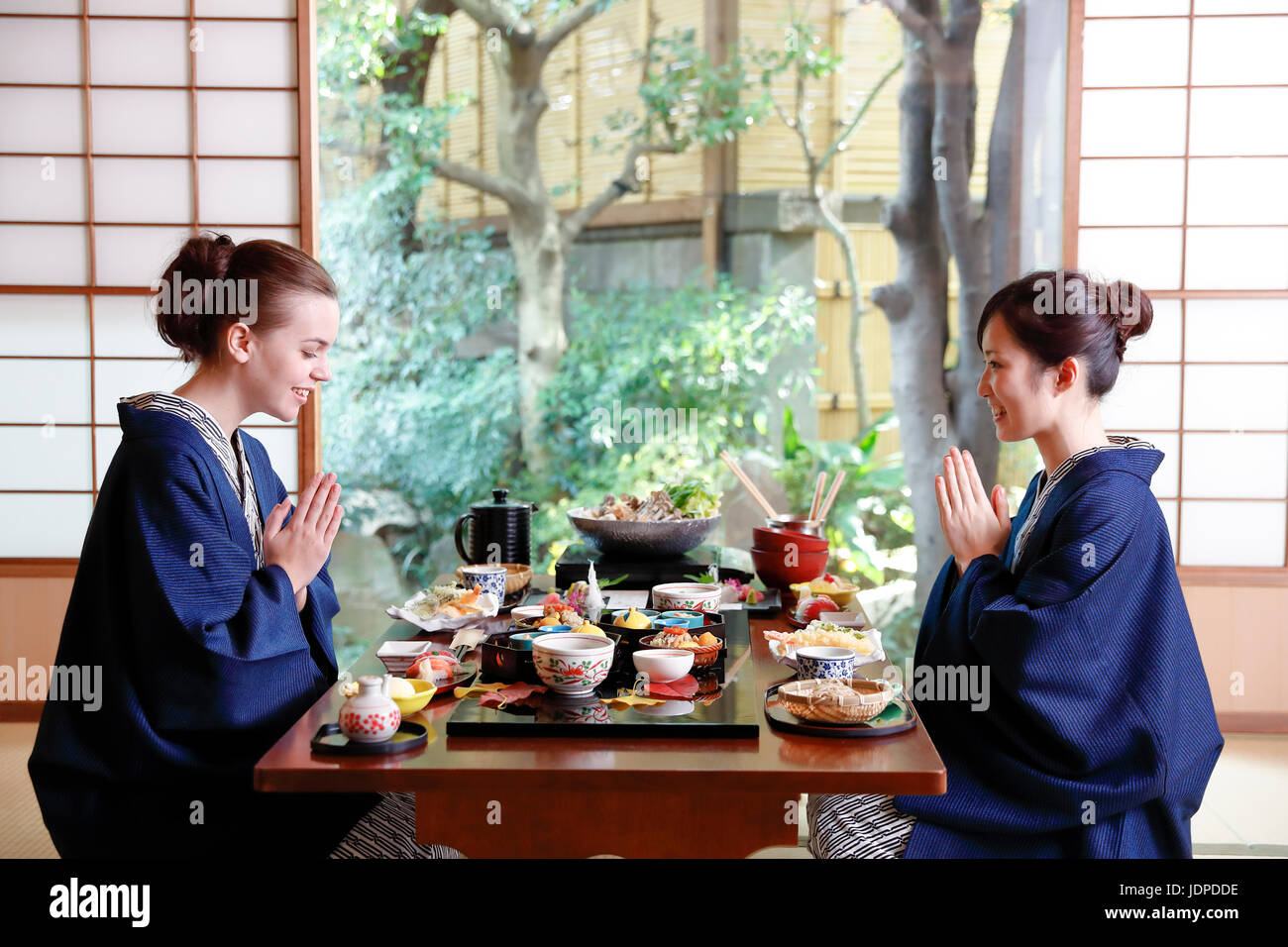 Kaukasische Trägerin Yukata Essen mit japanischer Freund im traditionellen Ryokan, Tokyo, Japan Stockfoto