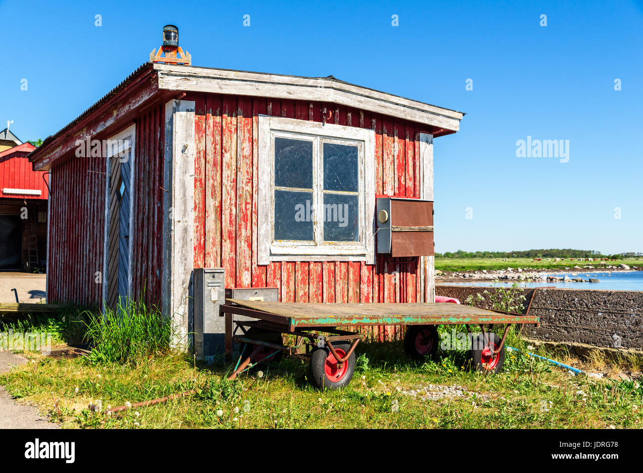 Verwitterte Angeln Kabine mit Wagen oder Waggon außerhalb. Küste mit sichtbaren Rinder im Hintergrund. Stockfoto