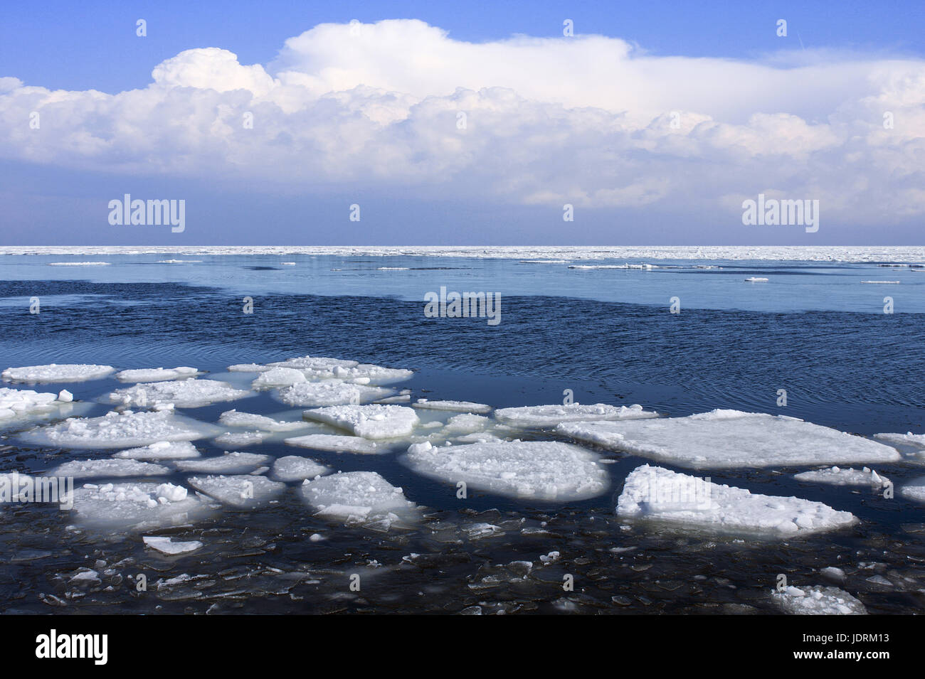 Frühling am Meer. Tauwetter, Debakel um das gefrorene Meer. Eisscholle diesseits, Wolken im Hintergrund. Stockfoto