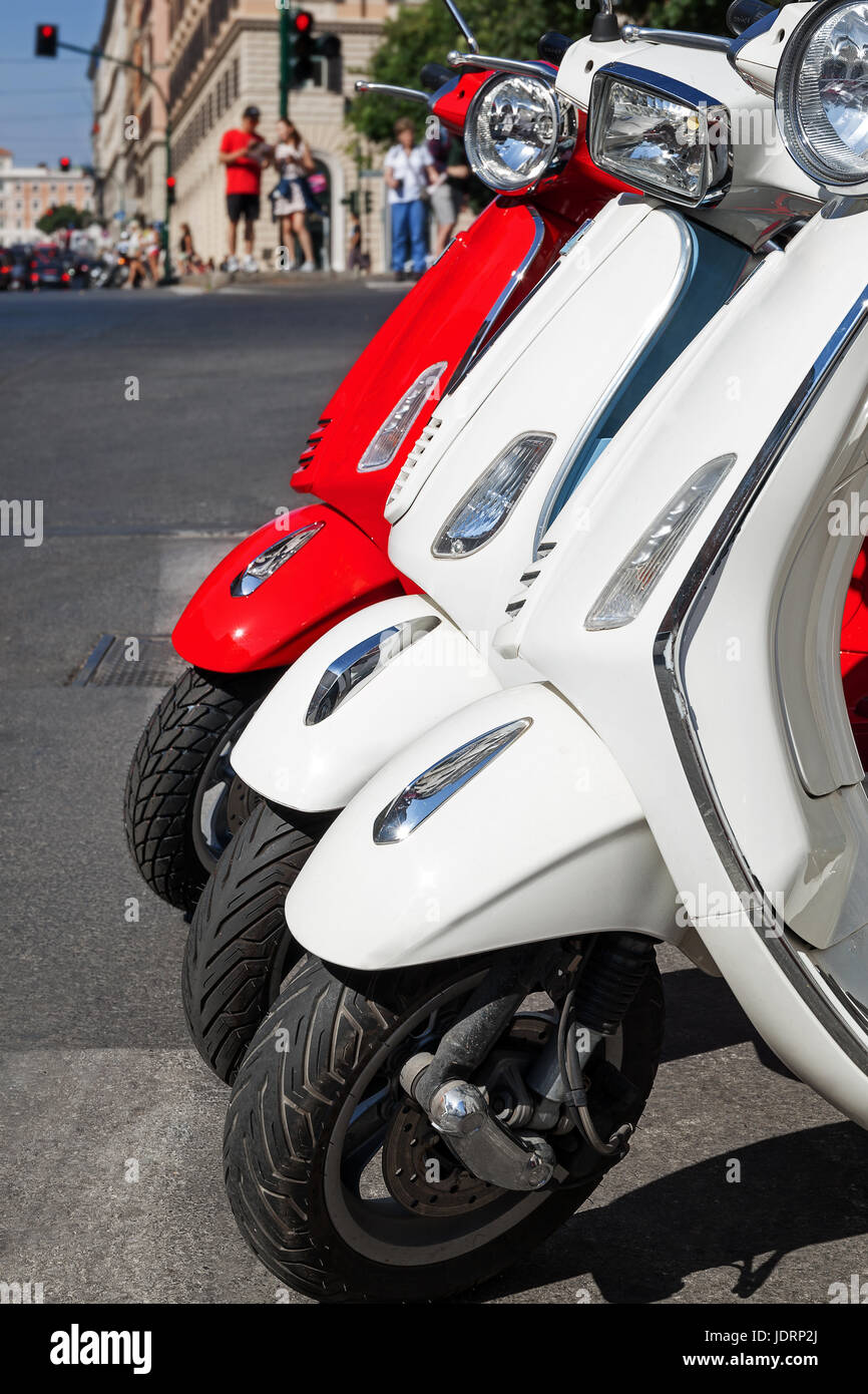 Motorroller Vespa-Modell, in einer Reihe am Rand der Straße geparkt. Rot / weiß Roller. Stockfoto