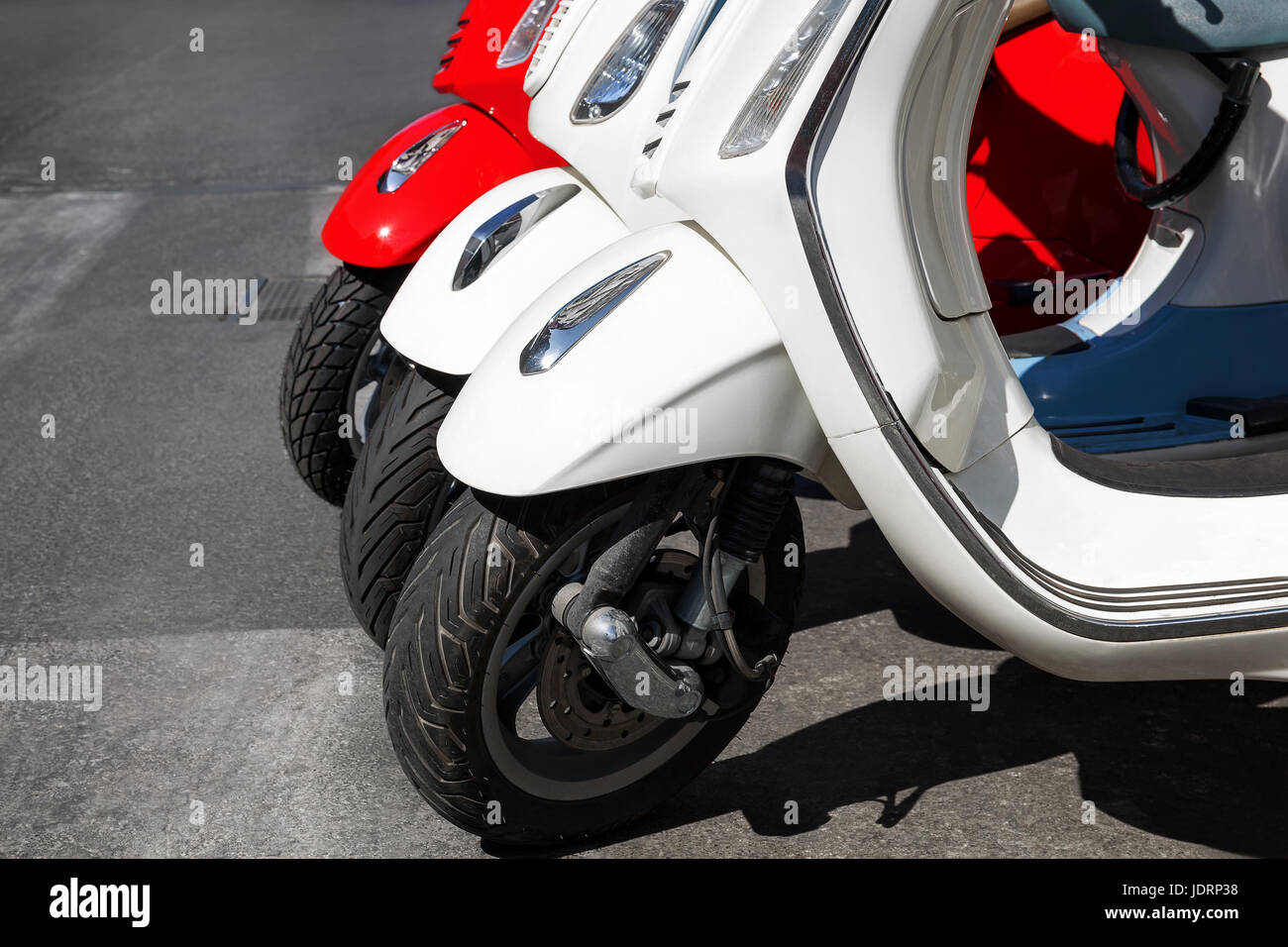 Motorroller Vespa-Modell, in einer Reihe am Rand der Straße geparkt. Rot / weiß Roller. Stockfoto