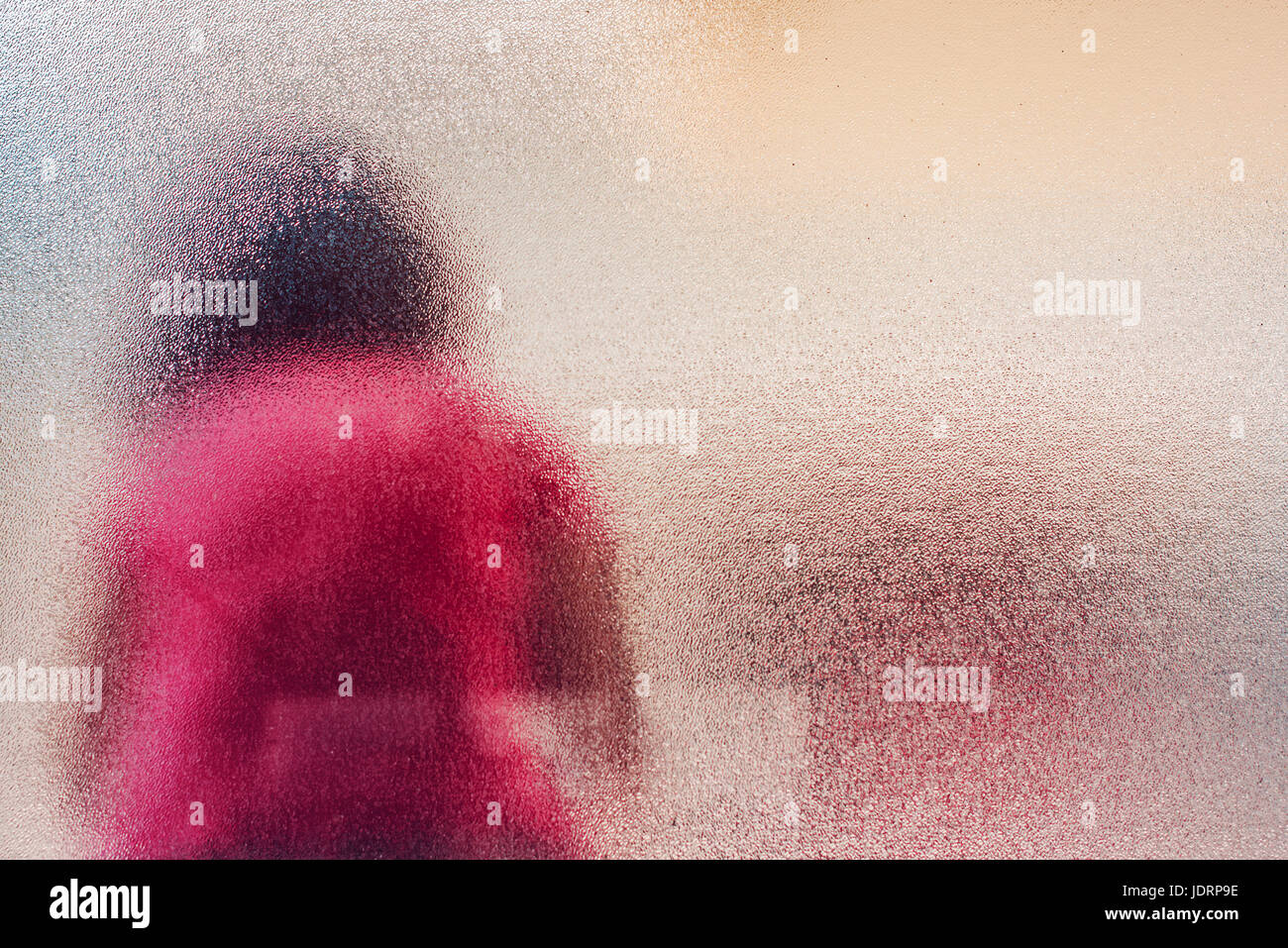 Silhouette der unkenntlich traurig autistisches Mädchen hinter Glasmalerei Fenster saß allein im Hinterhof Stockfoto
