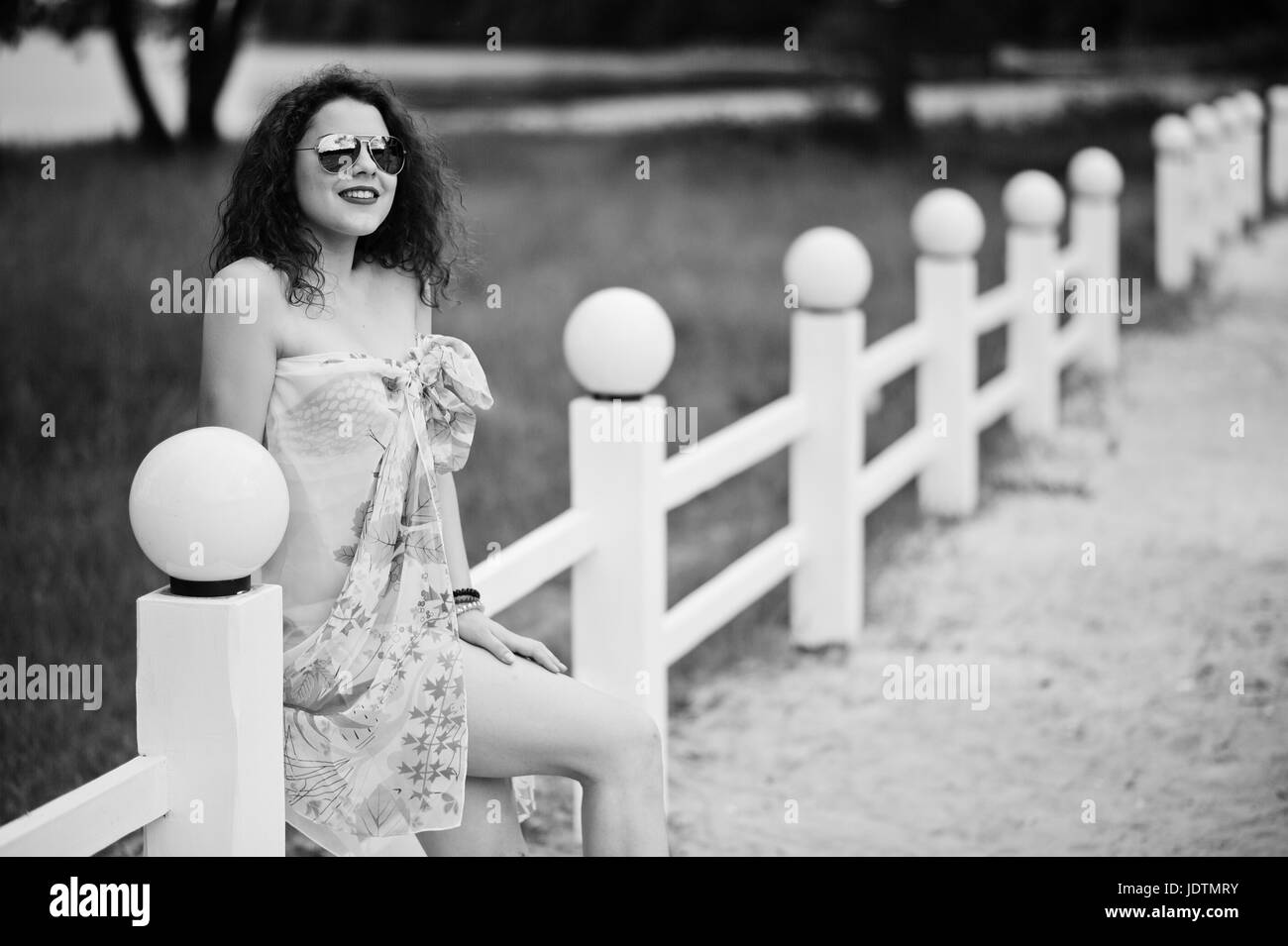 Porträt eines schönen Modells posieren gegen den Zaun in Sonnenbrillen in See. Schwarz / weiß Foto. Stockfoto