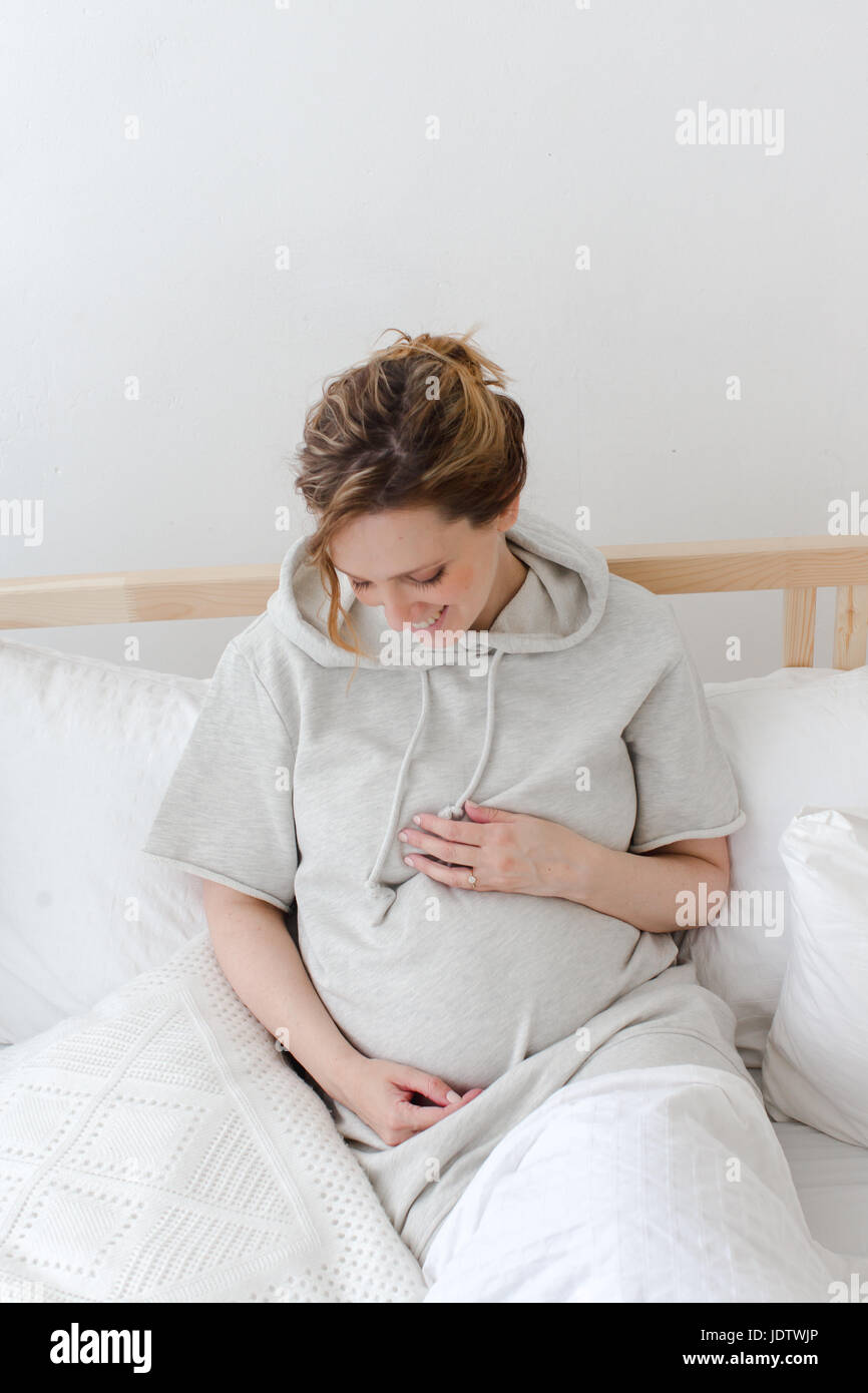 Schwangere lächelnd weibliche liegend auf Bett Stockfoto