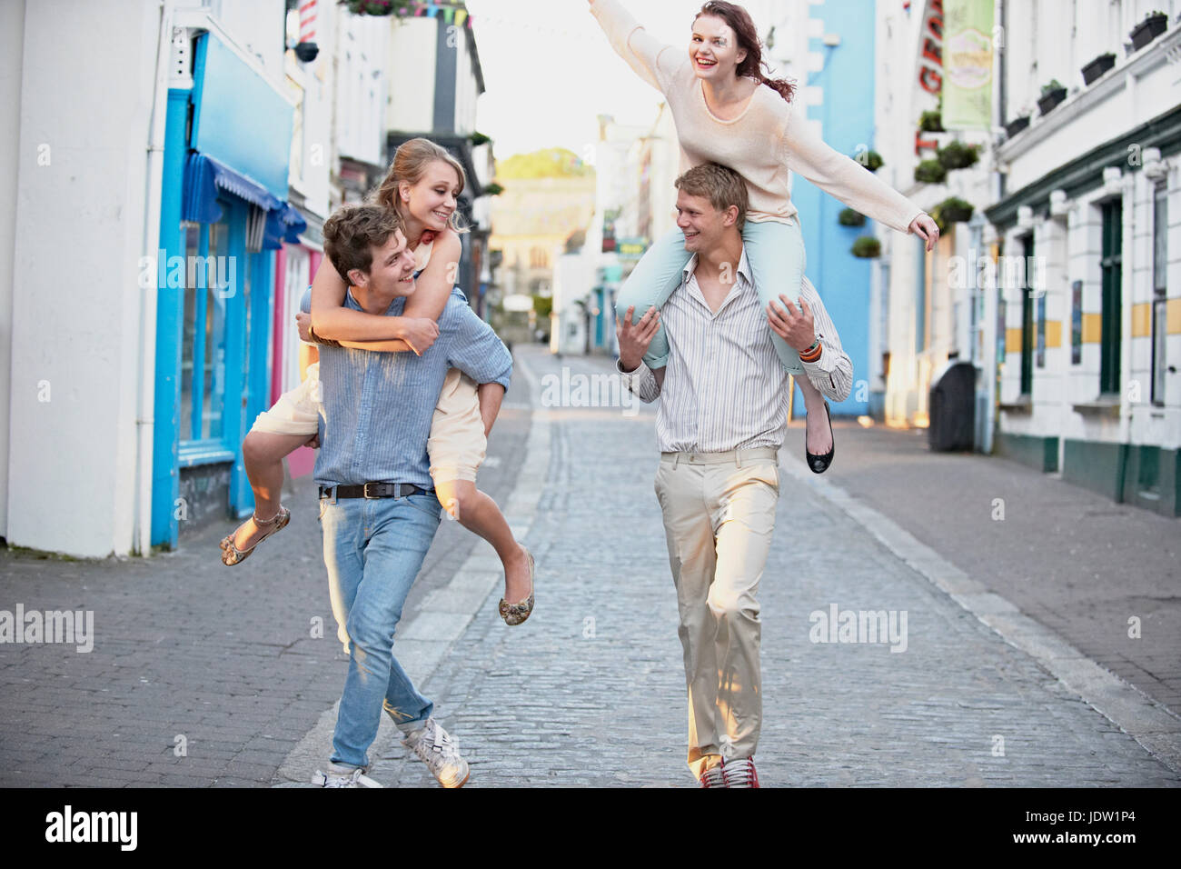 Männer tragen Freundinnen auf Stadtstraße Stockfoto