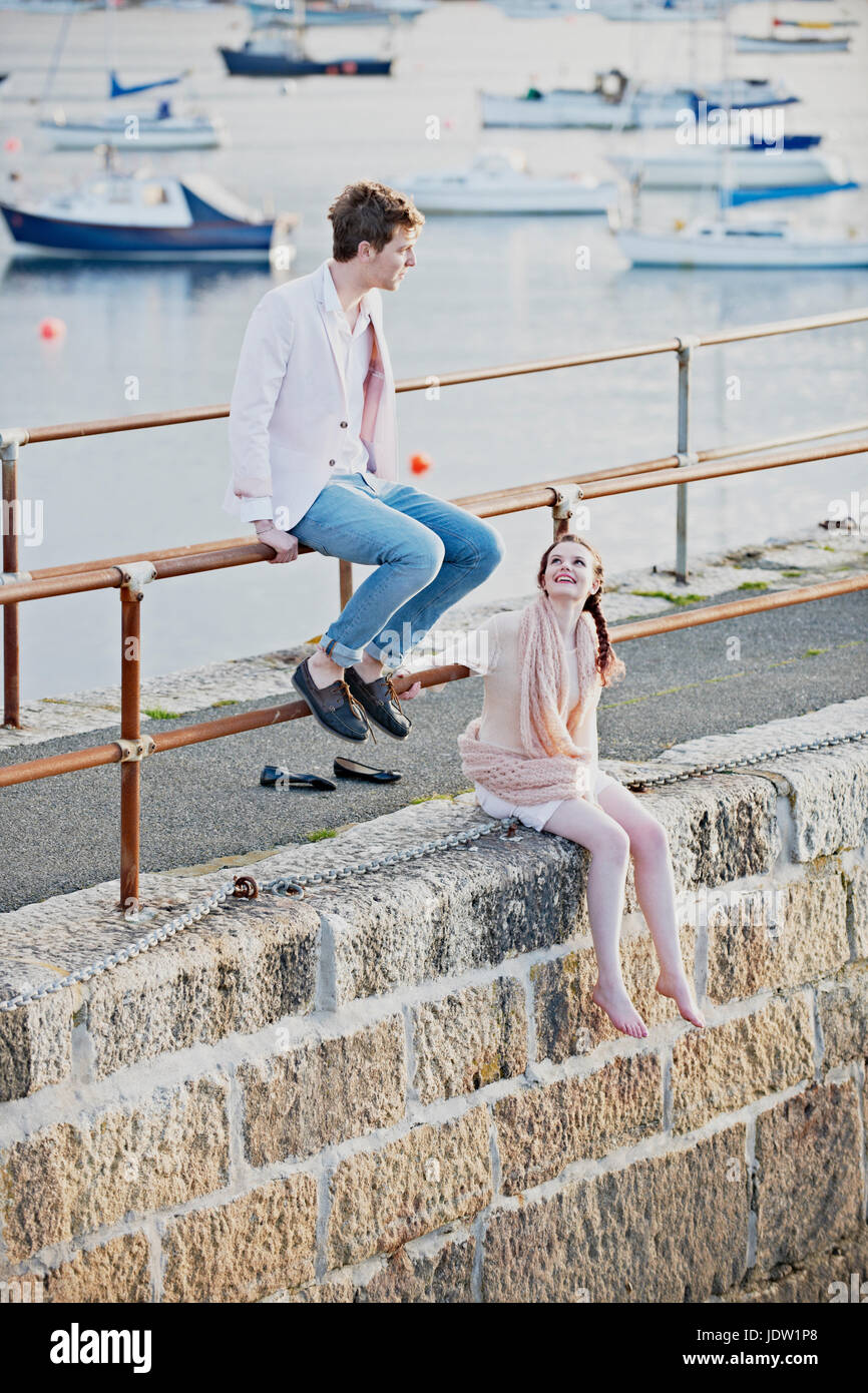 Paar sitzt am Geländer des Hafens Stockfoto