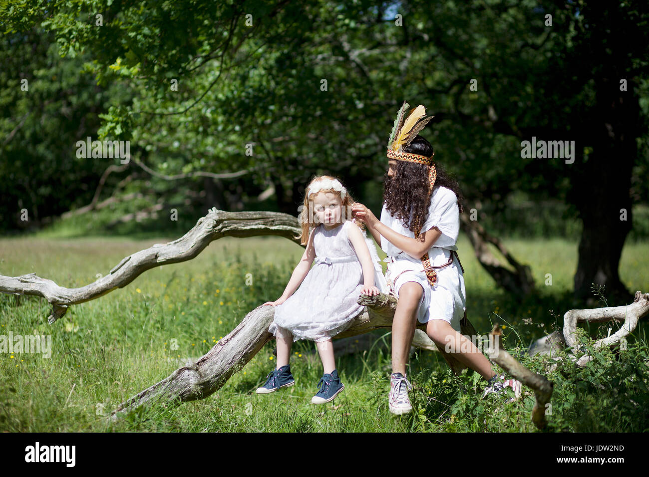 Mädchen in Tracht in Baum im freien Stockfoto