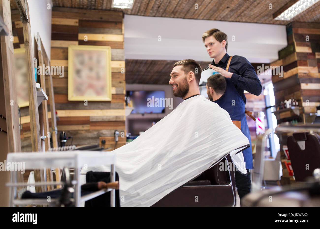 Mann und Friseur mit Spiegel im barbershop Stockfoto