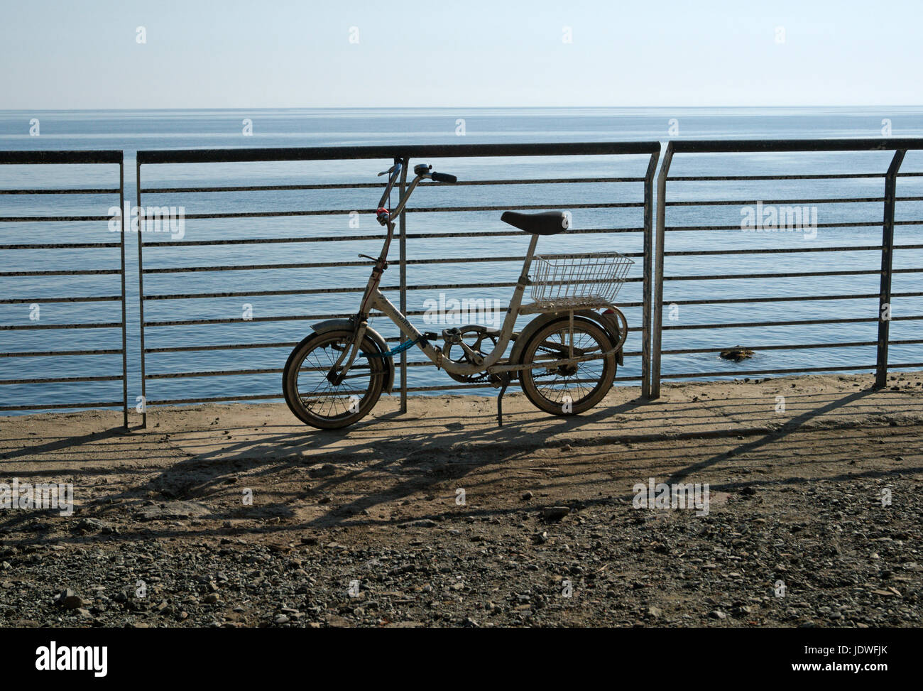 Kindergesundheit-Fahrrad mit Korb geparkt an Reling am Meer Stockfoto