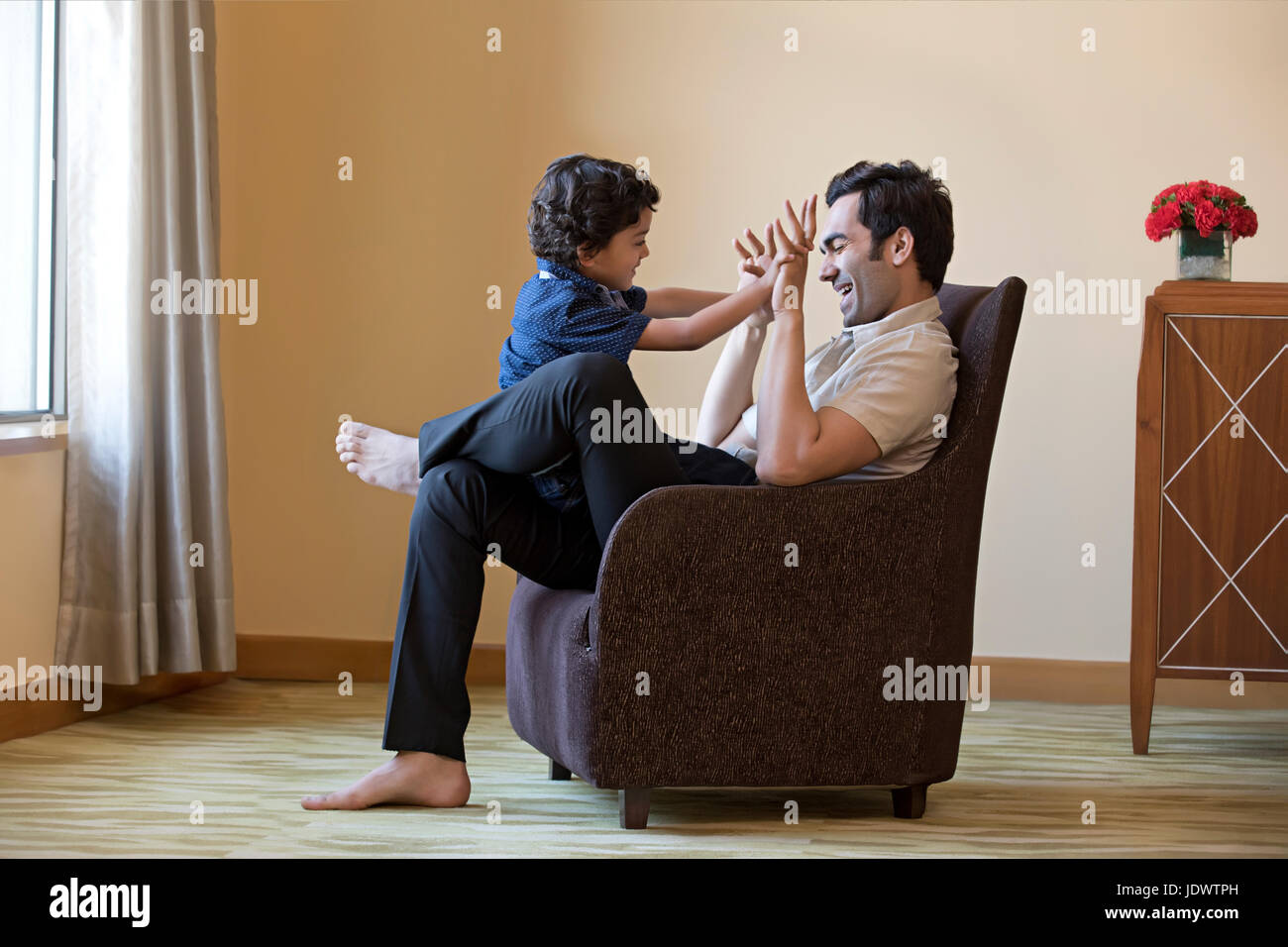 Junge Mann spielt mit seinem Sohn sitzt auf Sessel Stockfoto