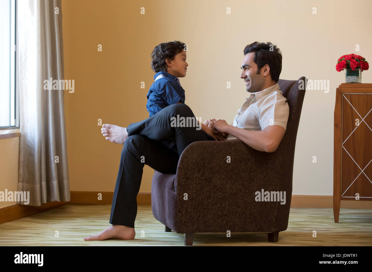 Vater und Sohn sitzen zusammen auf Sessel Stockfoto