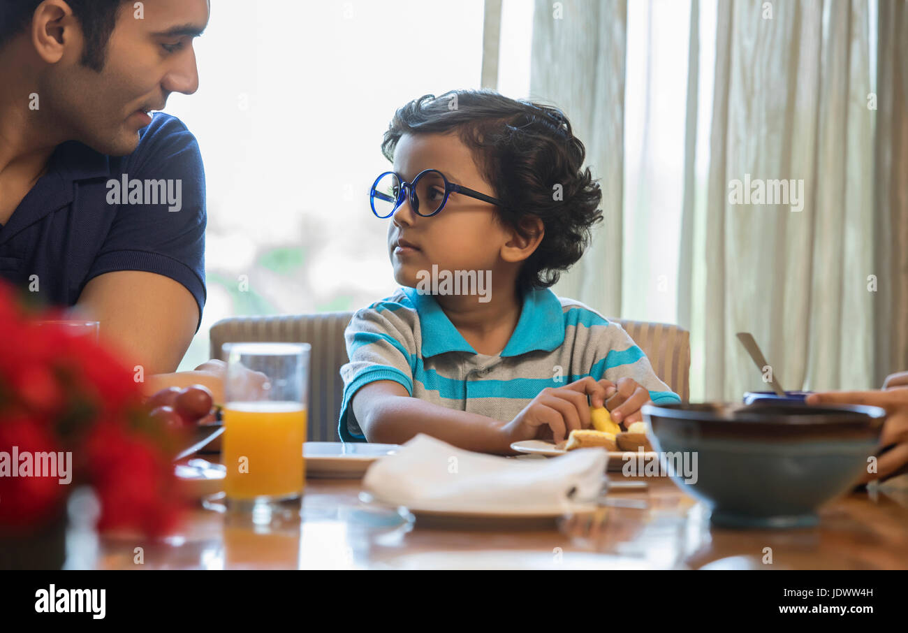Vater und Sohn sahen einander beim Essen bei Esstisch Stockfoto