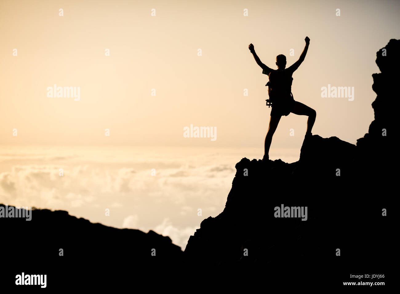 Mann erfolgreich Wandern Klettern Silhouette in Bergen, Motivation und Inspiration im wunderschönen Sonnenuntergang. Kletterer Arme ausgestreckt am Berg oben l Stockfoto