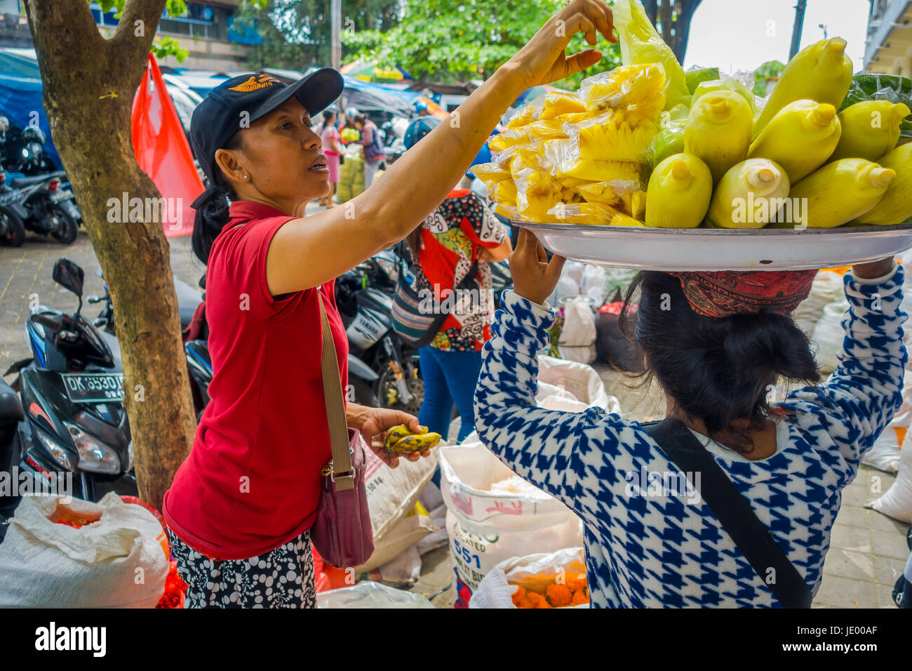 BALI, Indonesien - 8. März 2017: Unbekannte Frau einkaufen, während andere Frau, über ihrem Kopf Essen im Freien in Denpasar Stadt in der ich balanciert Stockfoto