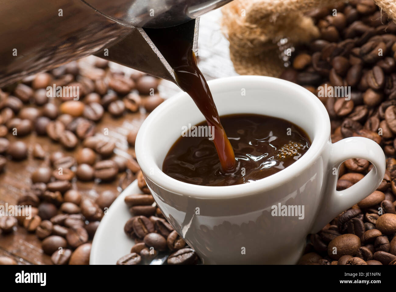 gießen Kaffee aus Kaffeekanne in Milchkaffee Tasse, Nahaufnahme. Stockfoto
