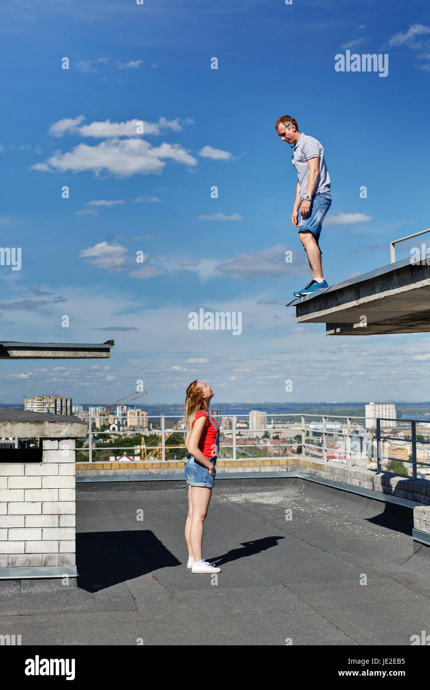 Ein Liebespaar der Dachdecker auf dem Dach. Der Mann und das Mädchen suchen sich gegenseitig. Romantik und Mut. Eine ungewöhnliche Datum. Stockfoto