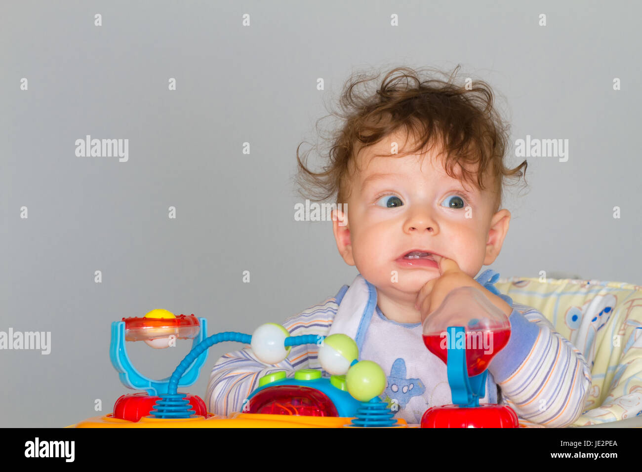 7 Monate alten Baby junge Porträt bei Walker mit Finger in den Mund. Stockfoto