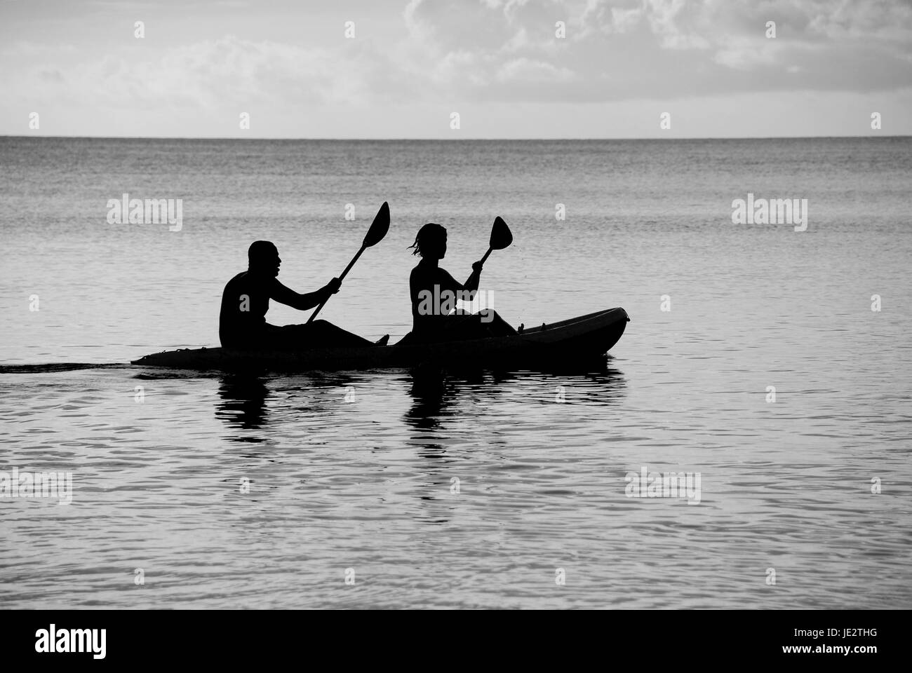 Mann und Frau auf dem Meer in einem Kajak - Silhouette monochrome Verarbeitung Stockfoto