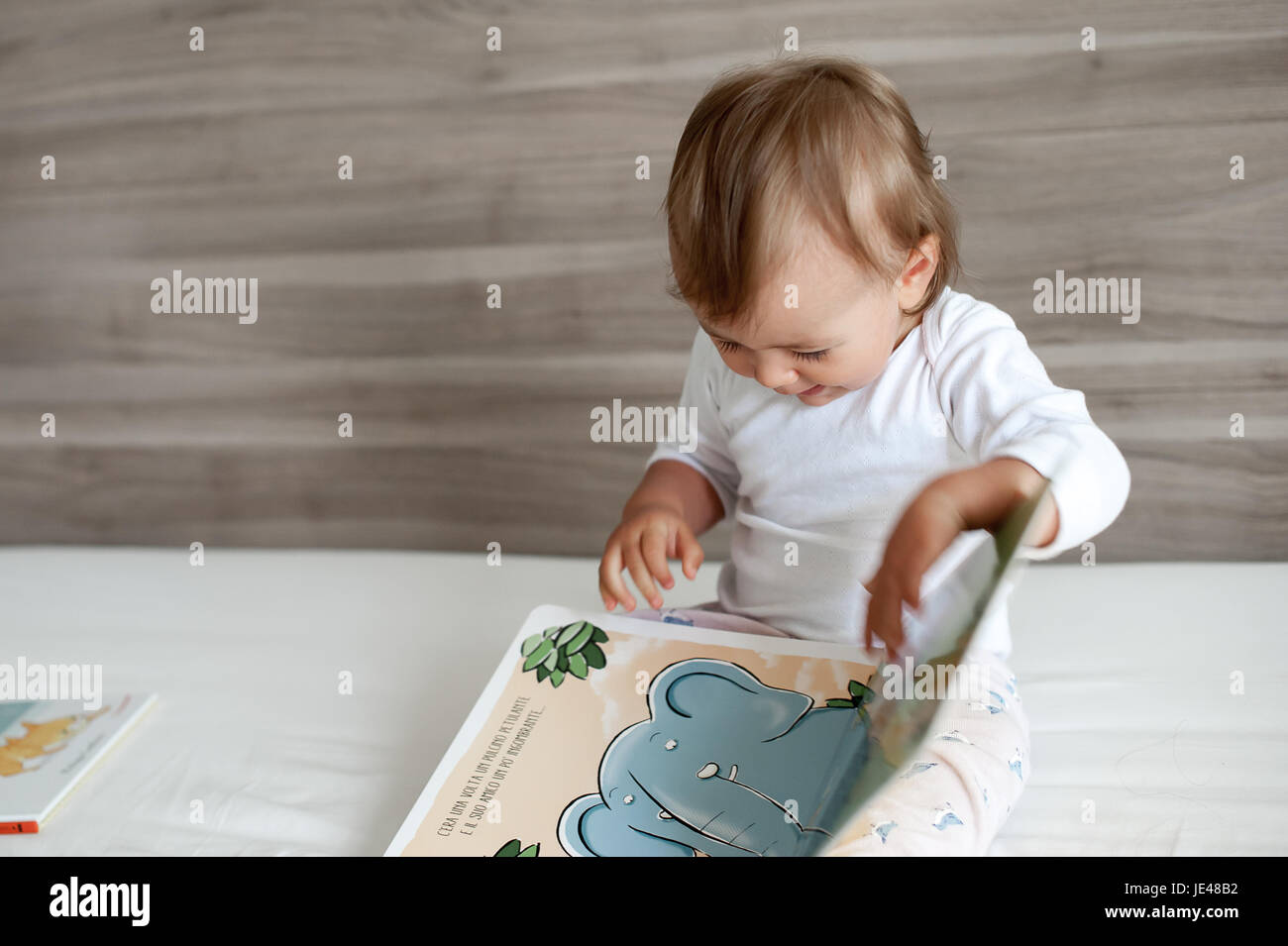 Einjähriges Kind eine bunte Kinder-Buch zu betrachten. Stockfoto