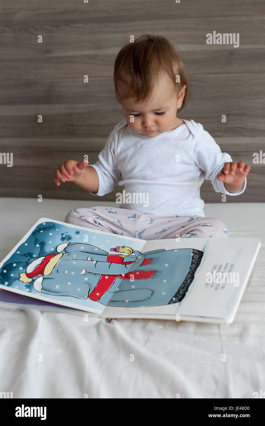 Einjähriges Kind eine bunte Kinder-Buch zu betrachten. Stockfoto