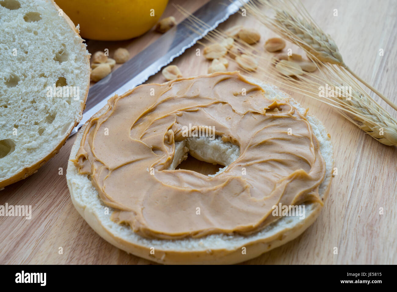 Sesam-Bagel mit Erdnussbutter auf ein Schneidebrett mit Messer Stockfoto