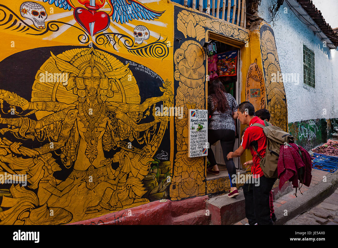 Bogotá, Kolumbien - Tourist überprüft eine Liste vor einem traditionellen Geschäft in den engen, bunten, Kopfsteinpflaster Calle del Embudo in La Candelaria. Stockfoto Bogotá, Kolumbien - Tourist überprüft eine Liste vor einem traditionellen Geschäft in den engen, bunten, Kopfsteinpflaster Calle del Embudo in La Candelaria. Stockfoto