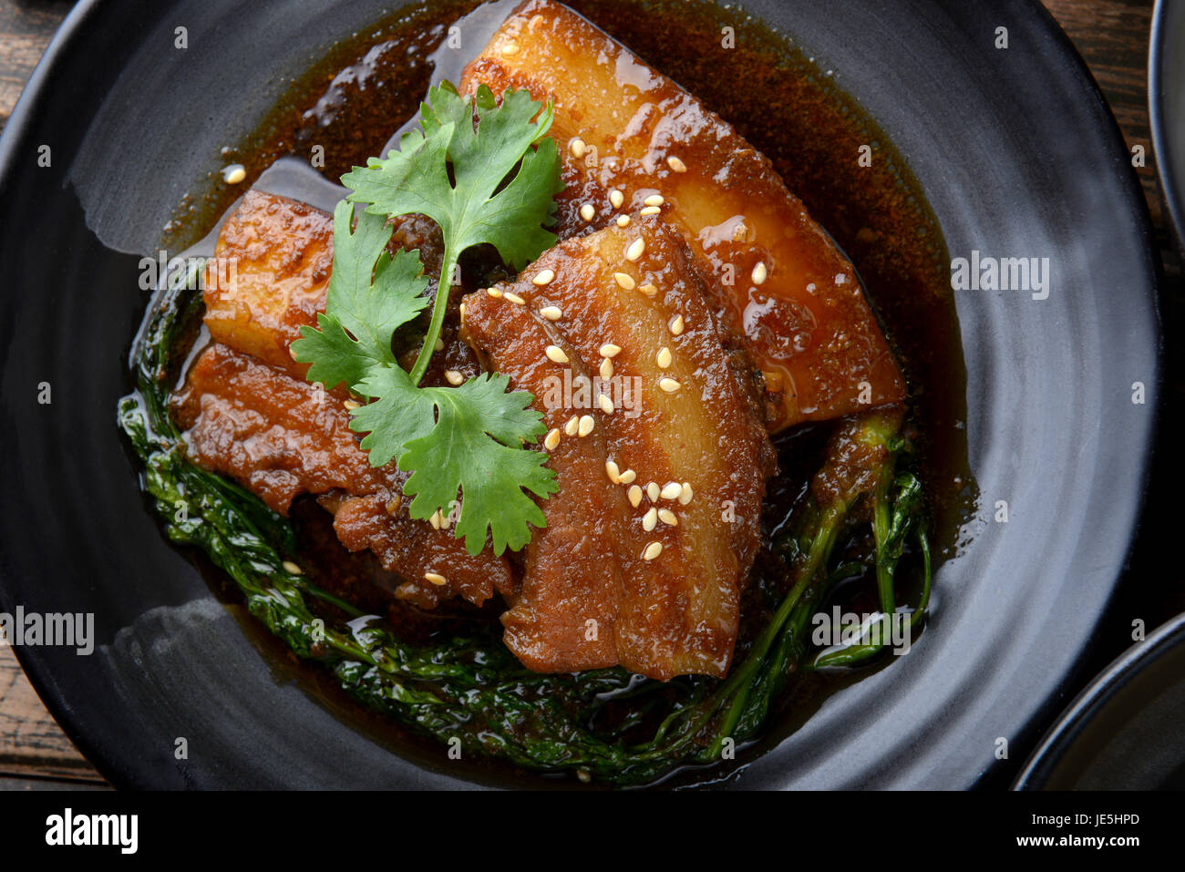 Chinesische süß gedünstet Schwein Einstellung auf schwarzen japanischen Stil Teller in Studiobeleuchtung. Stockfoto