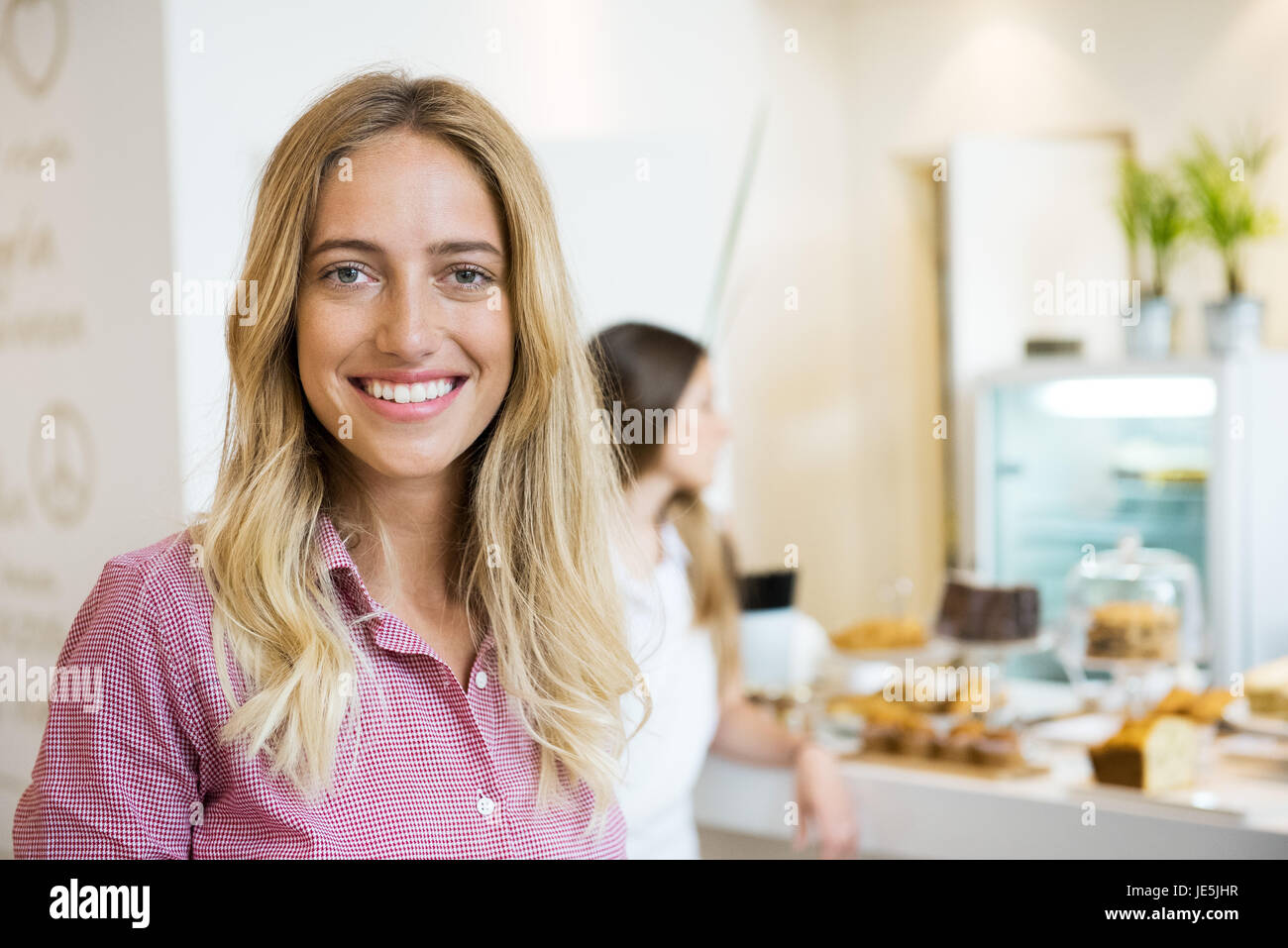 Junge Frau fröhlich lächelnd in Bäckerei, Porträt Stockfoto