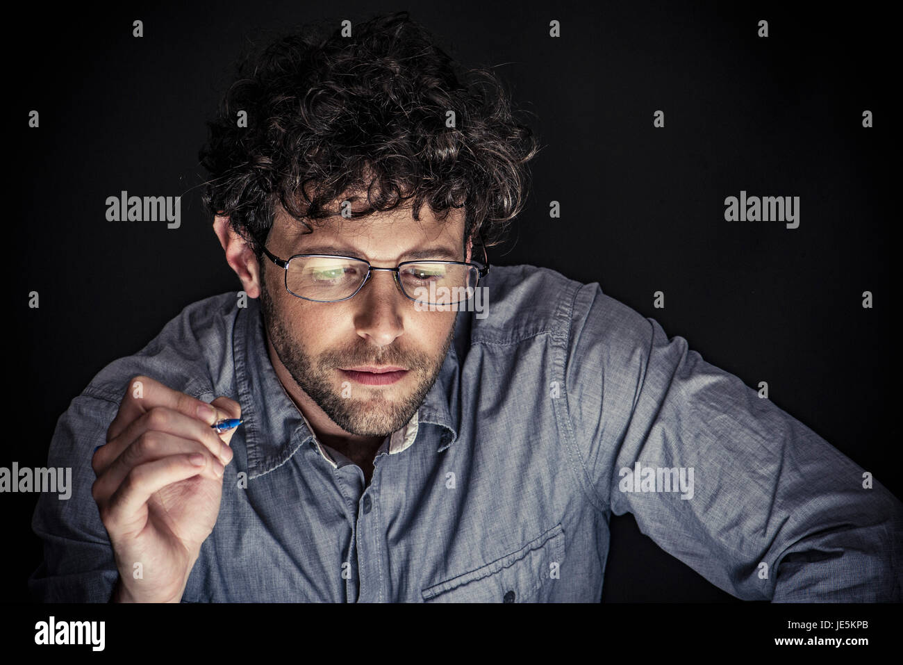 Mann hält Stift und blickte in Konzentration Stockfoto