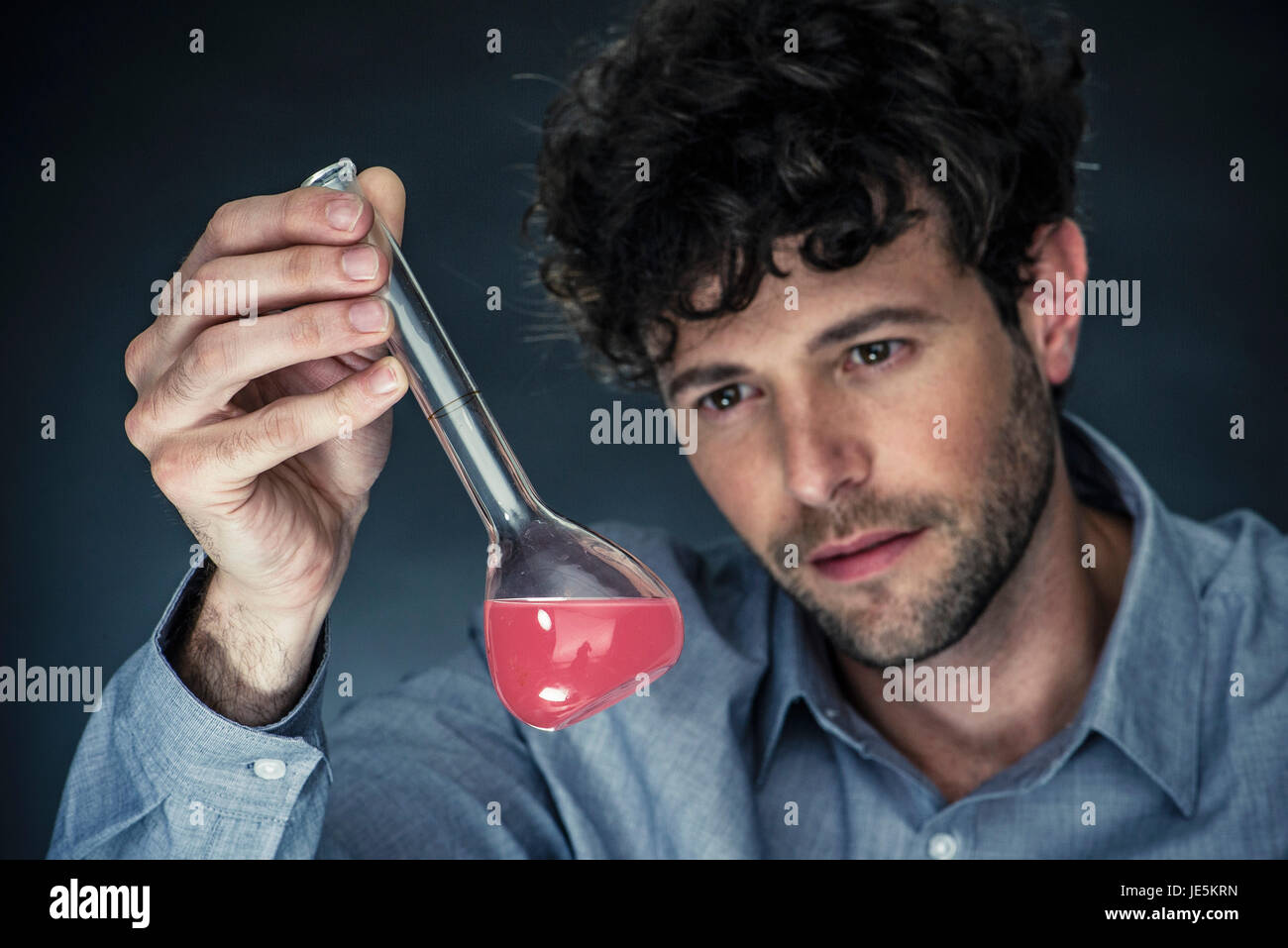 Mann auf der Suche an Flüssigkeit in konischen Kolben Stockfoto