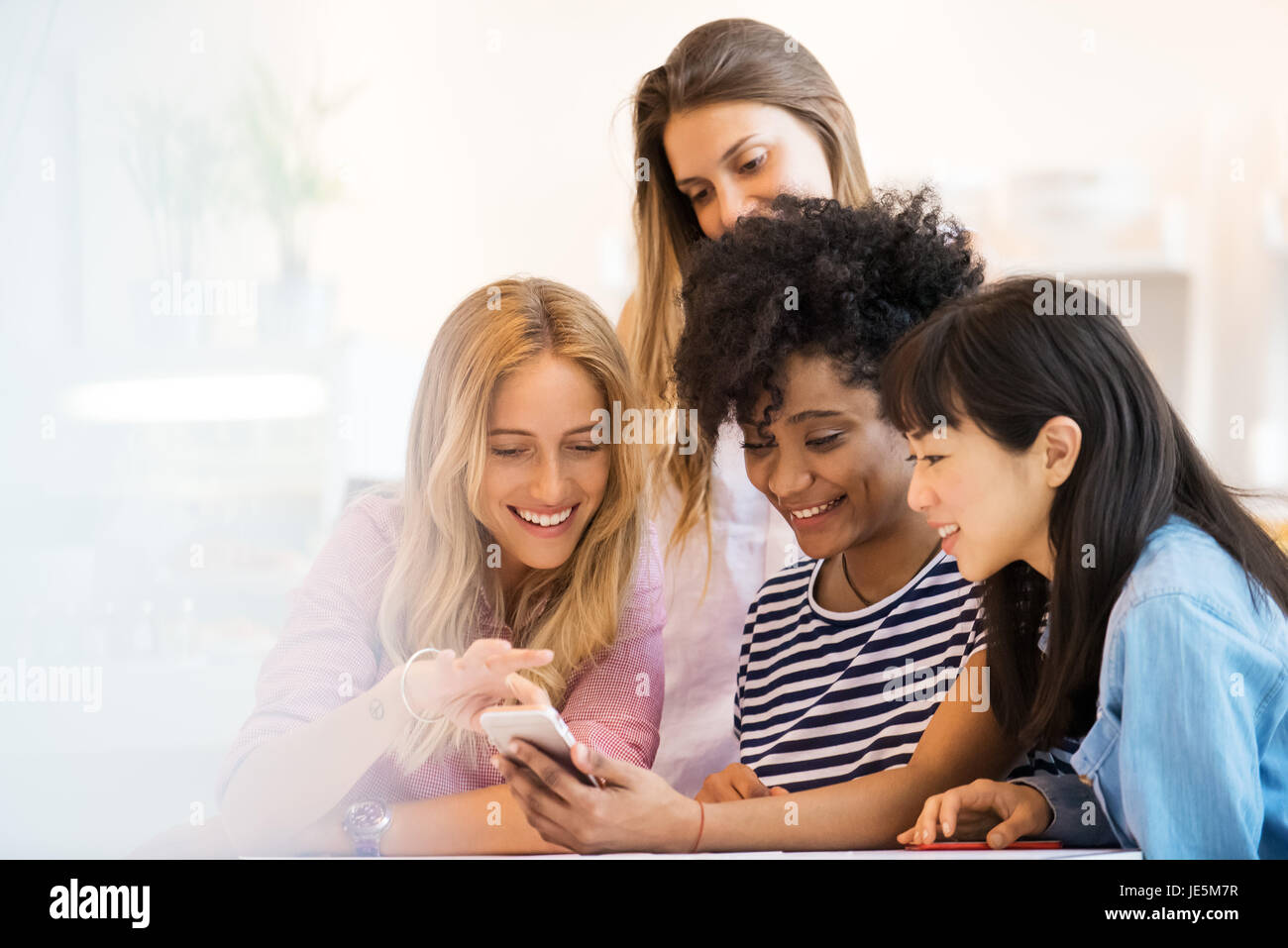 Junge Frauen auf der Suche auf Smartphone zusammen Stockfoto