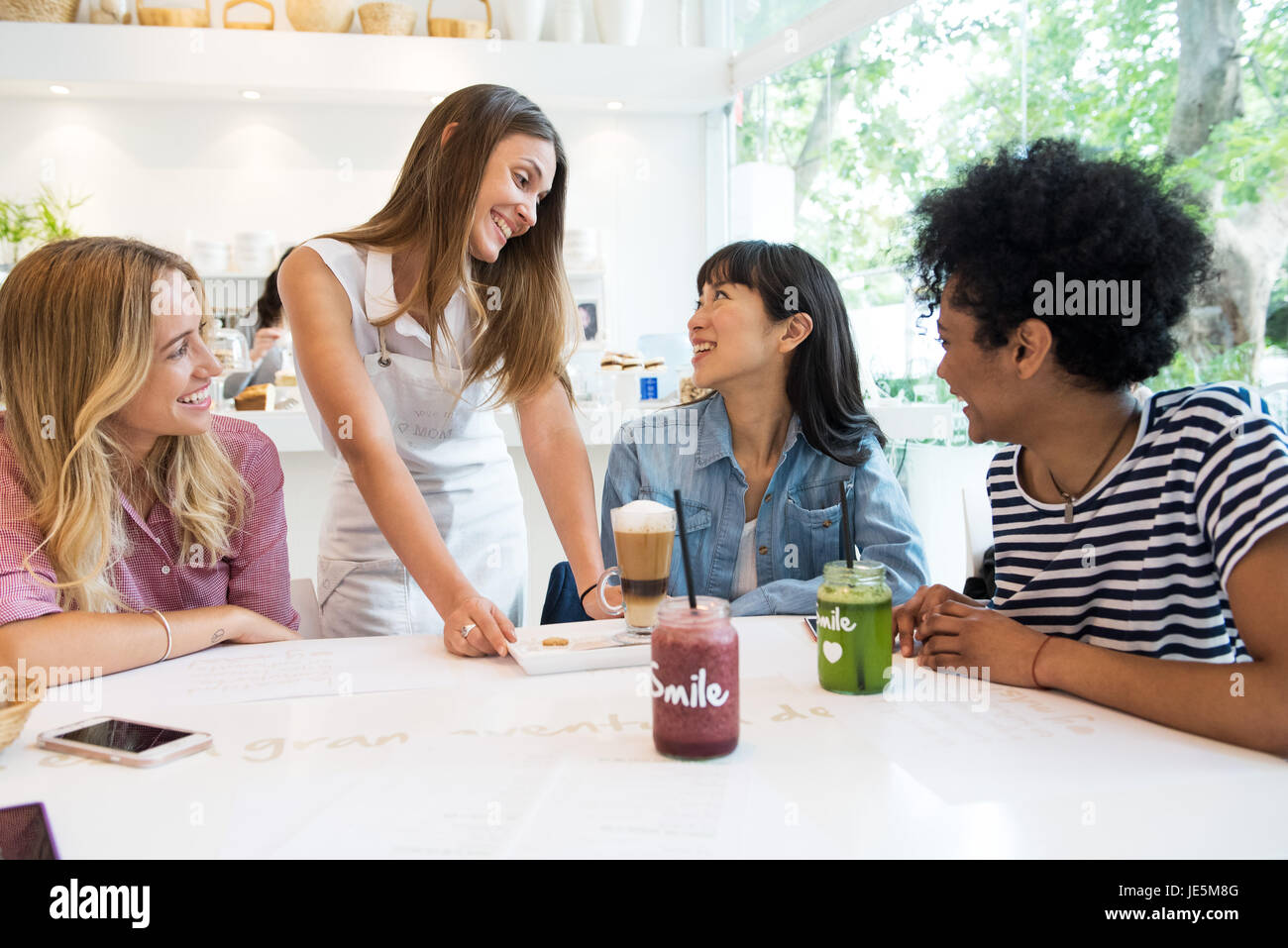 Kellnerin serviert Drinks zu Gruppe von Frauen im café Stockfoto