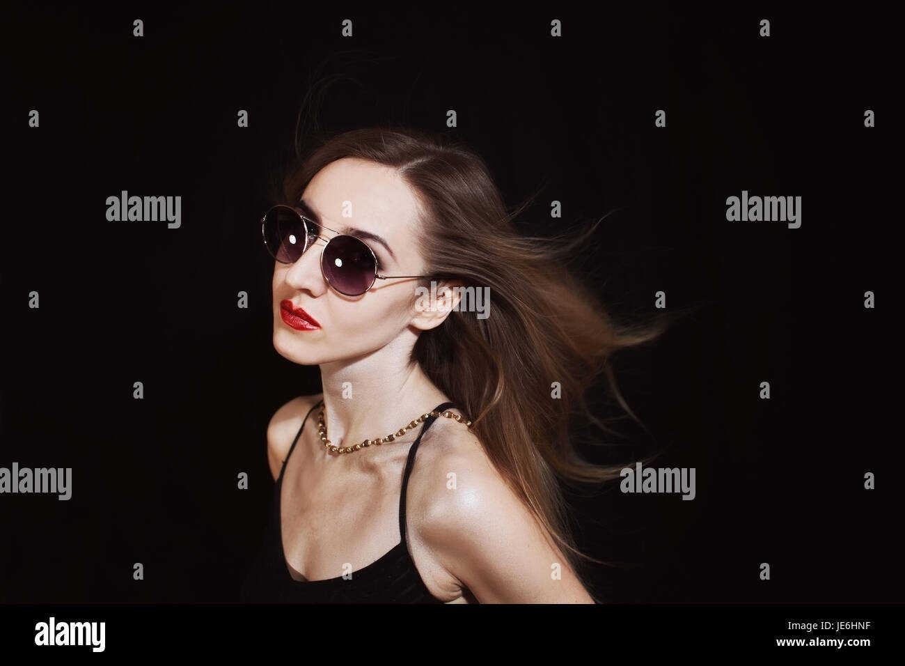 Studio-Porträt einer jungen schönen Frau mit einer Sonnenbrille auf schwarzem Hintergrund. Modefoto Stockfoto