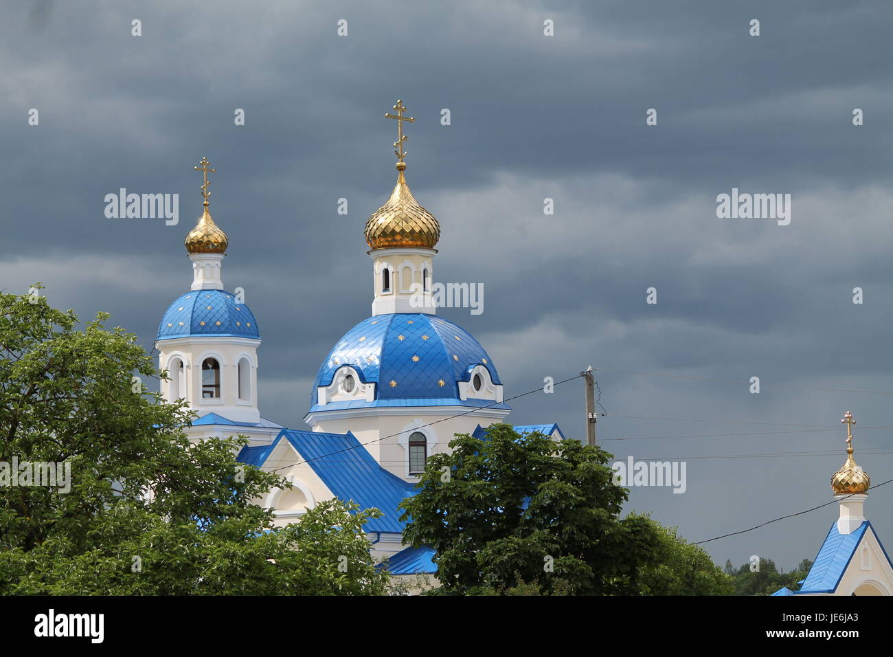 Spitze der orthodoxen Kirche mit der goldenen Kuppel Sünde im Sommer grün vor Sturm Stockfoto