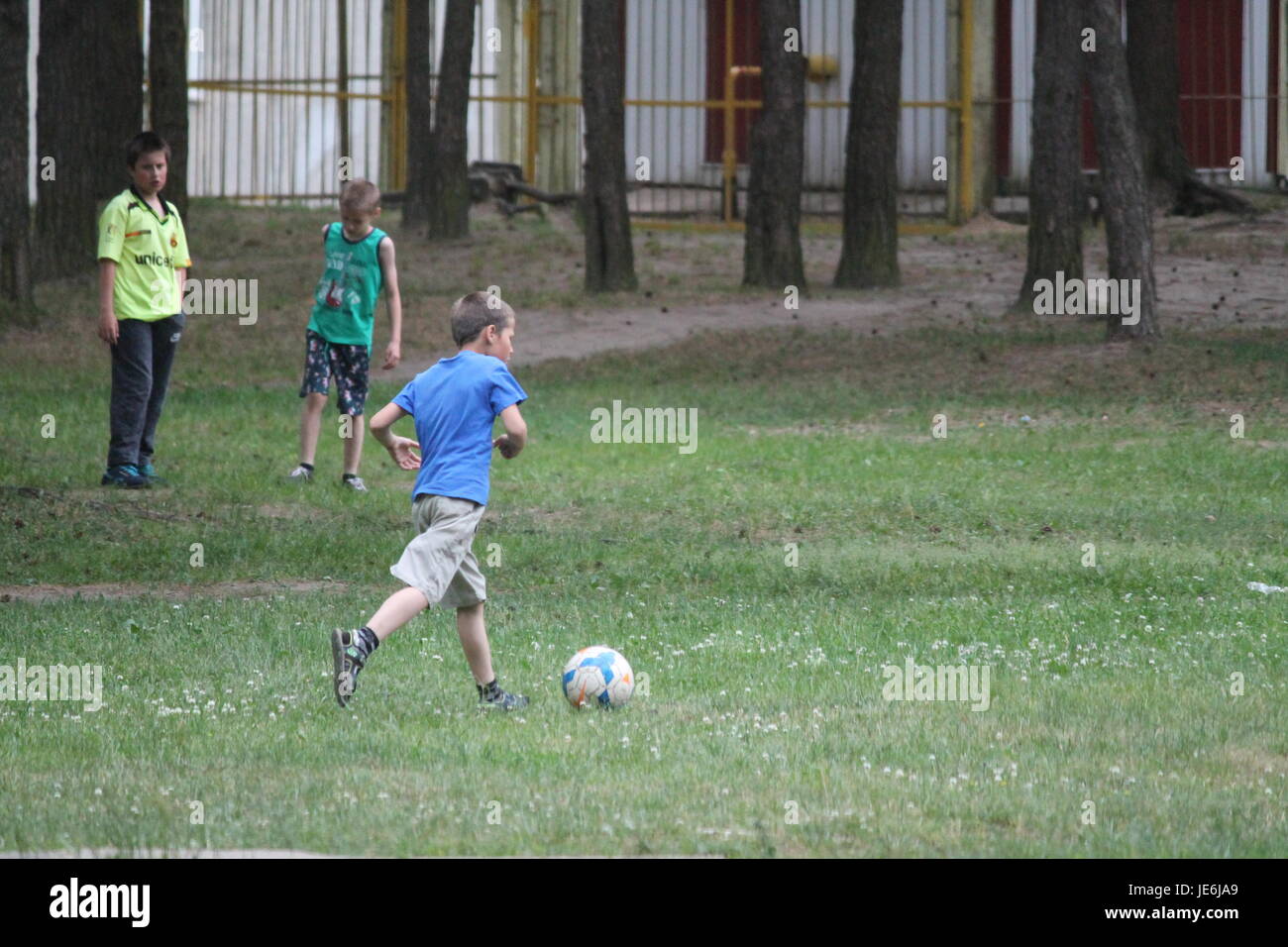 kleine lebendige junge mit Fußball-Ball schnell laufen versuchen, Ziel zu schlagen Stockfoto