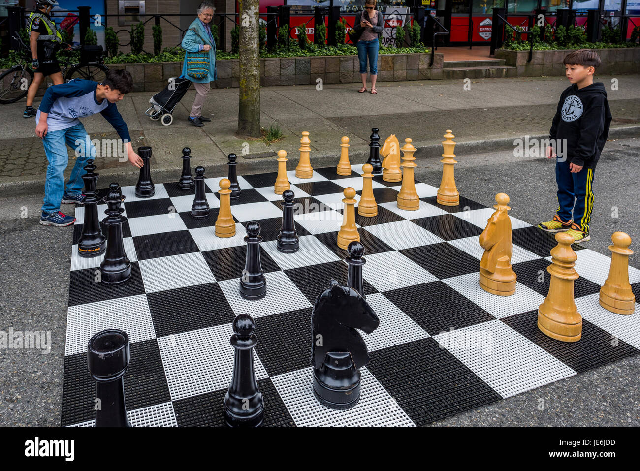 Jungs spielen großes Stück Schach im freien Spiel, autofreien Tag, West End, Vancouver, Britisch-Kolumbien, Kanada. Stockfoto