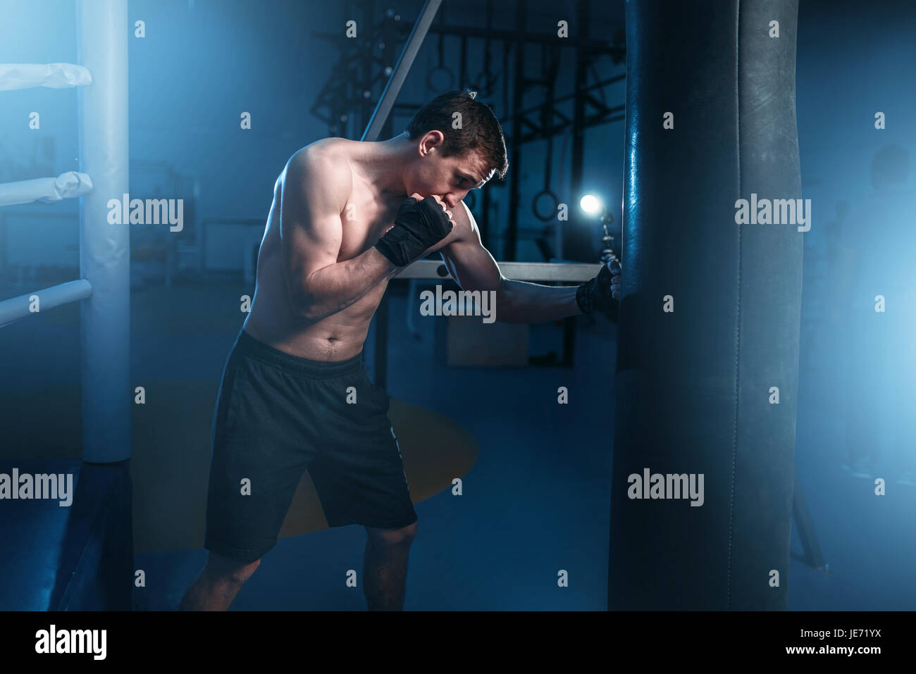 Mann in schwarz Boxbandagen Übungen mit Tasche im Fitness-Studio. Boxtraining, Herren sport Stockfoto