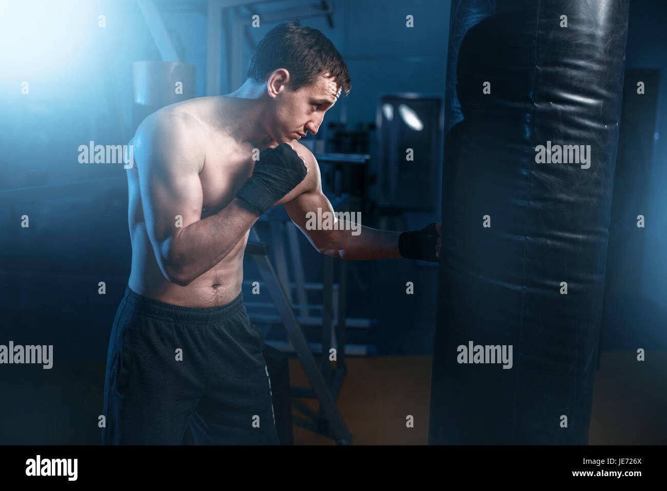 Mann in schwarz Boxbandagen Übungen mit Tasche im Fitness-Studio. Boxtraining, Herren sport Stockfoto