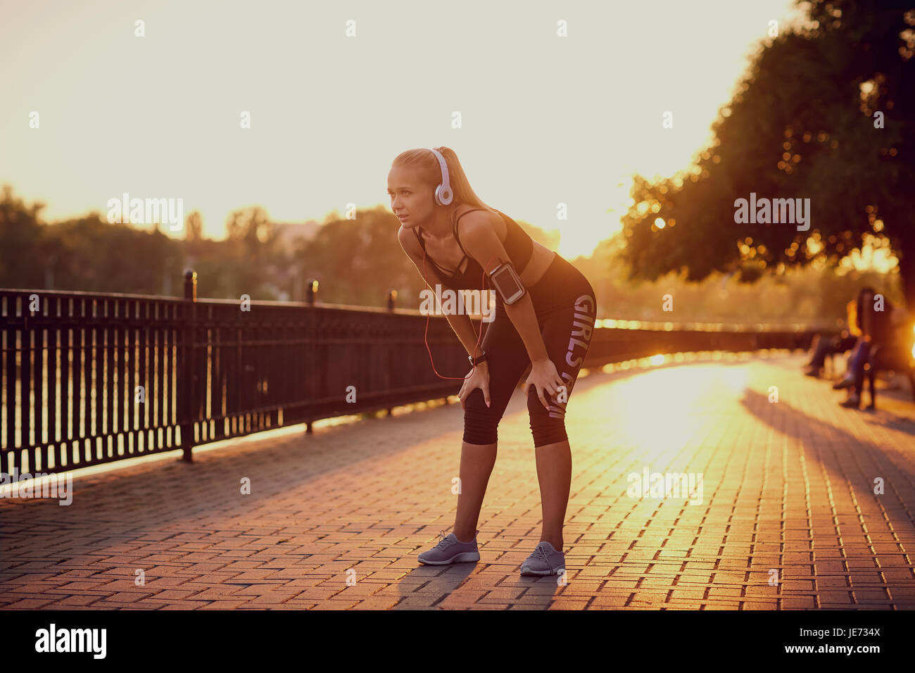 Mädchen im Kopfhörer auf einen Lauf im Park bei Sonnenuntergang Stockfoto