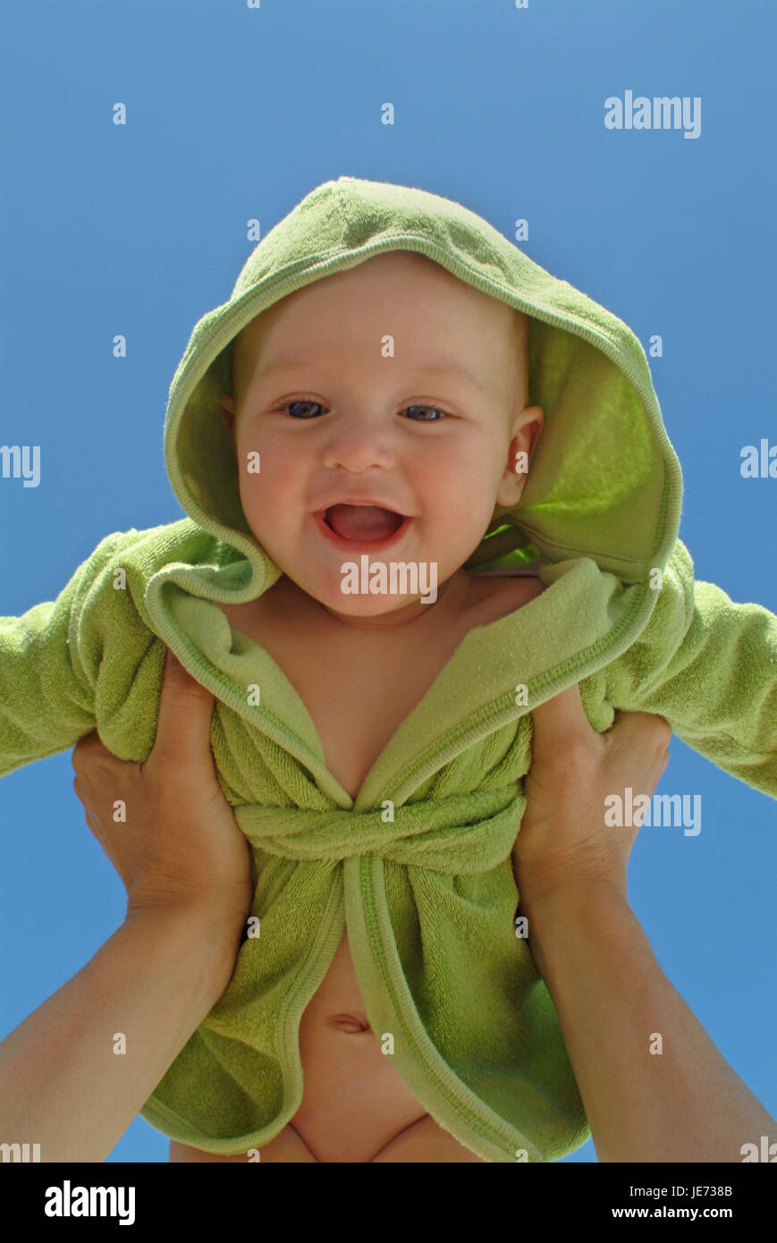 6 Monate altes Baby wird von Eltern, fröhlich, lachen, blauen Himmel gehoben, Stockfoto