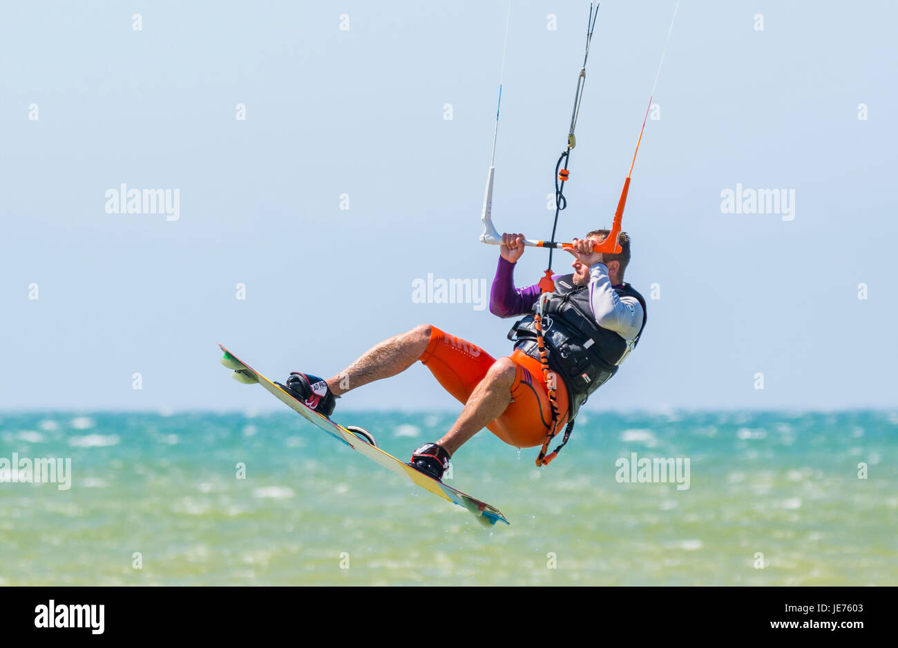 Kitesurfer fliegen in der Luft, wie er einen Stunt während auf dem Meer an einem windigen Tag. Stockfoto
