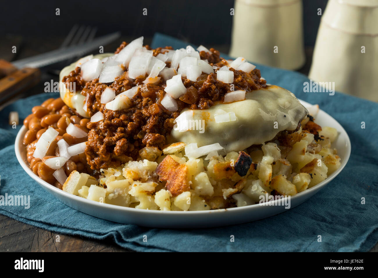 Ungesunde hausgemachte Rindfleisch Müll Müll Teller mit Kartoffeln Bohnen Makkaroni Salat und Cheeseburger Stockfoto